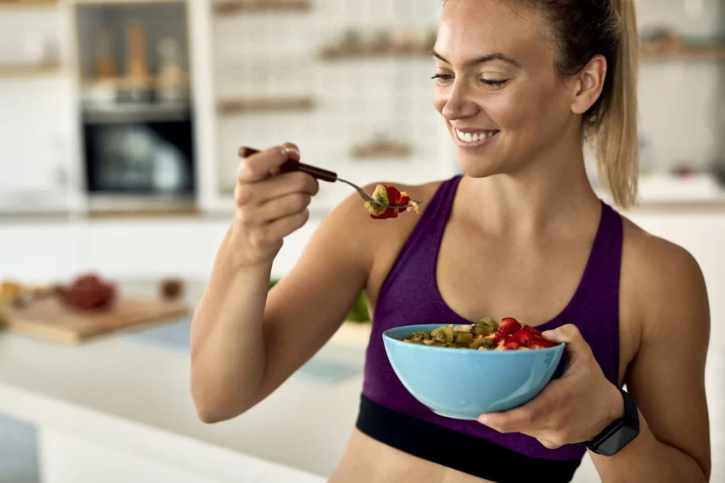 Une femme qui mange un bol de salade de fruit