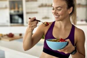 Une femme qui mange un bol de salade de fruit
