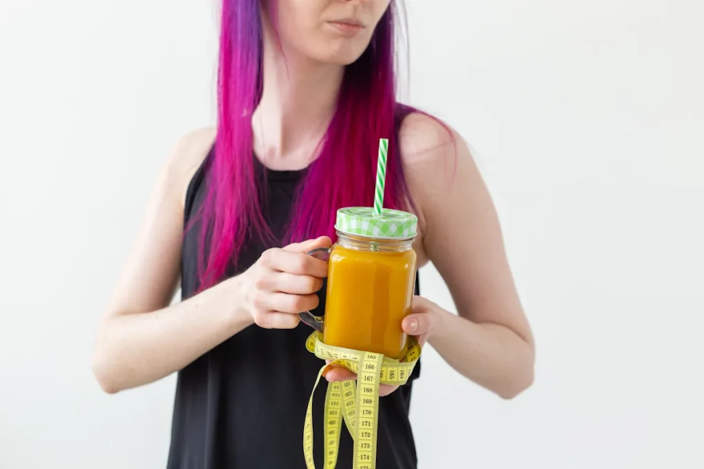 Une femme qui tient une boisson dans un verre et un mettre à ruban